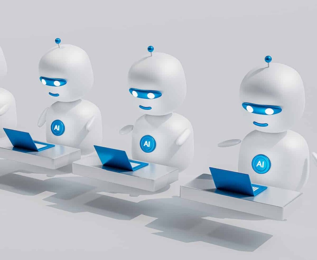 a group of white robots sitting on top of laptops