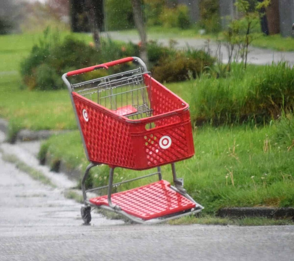 a red shopping cart sitting on the side of a road
